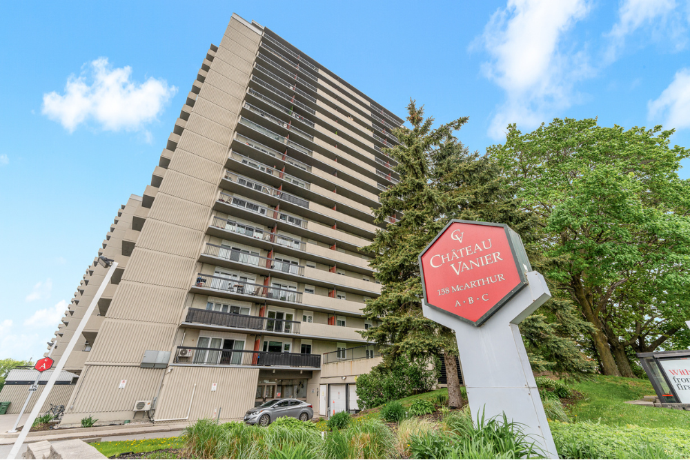 Front view of Chateau Vanier high-rise condominium at 158A McArthur Avenue in Vanier Ottawa, showcasing the building’s entrance and sign surrounded by greenery. Anna Alemi Real Estate team best realtor in ottawa.