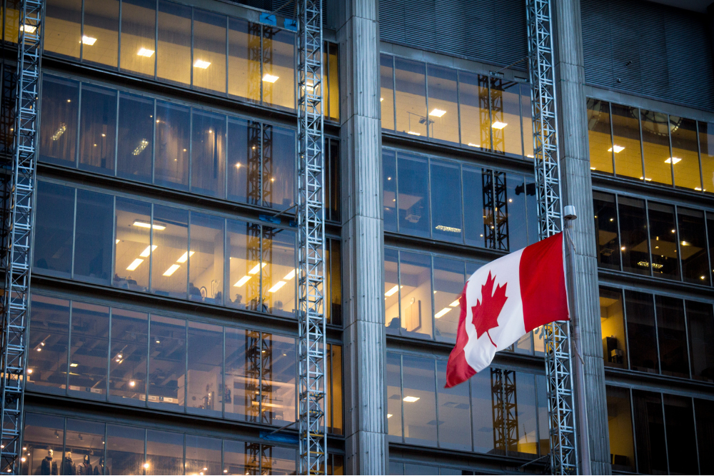 Canadian flag in front of a modern office building in Ontario, representing the 2026 housing supply and real estate market trends