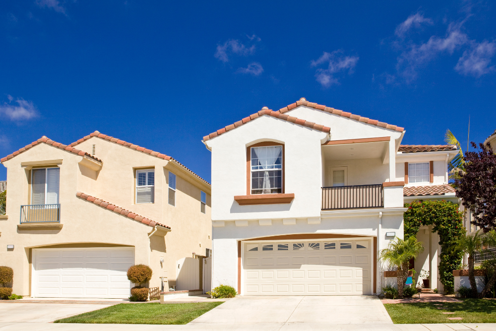 Two modern suburban detached homes with garages under a clear blue sky representing housing trends in the Ottawa real estate market
