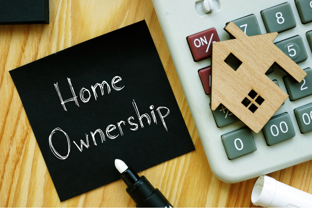 Renting vs buying in Ottawa concept with home ownership note, calculator, and wooden house model on desk